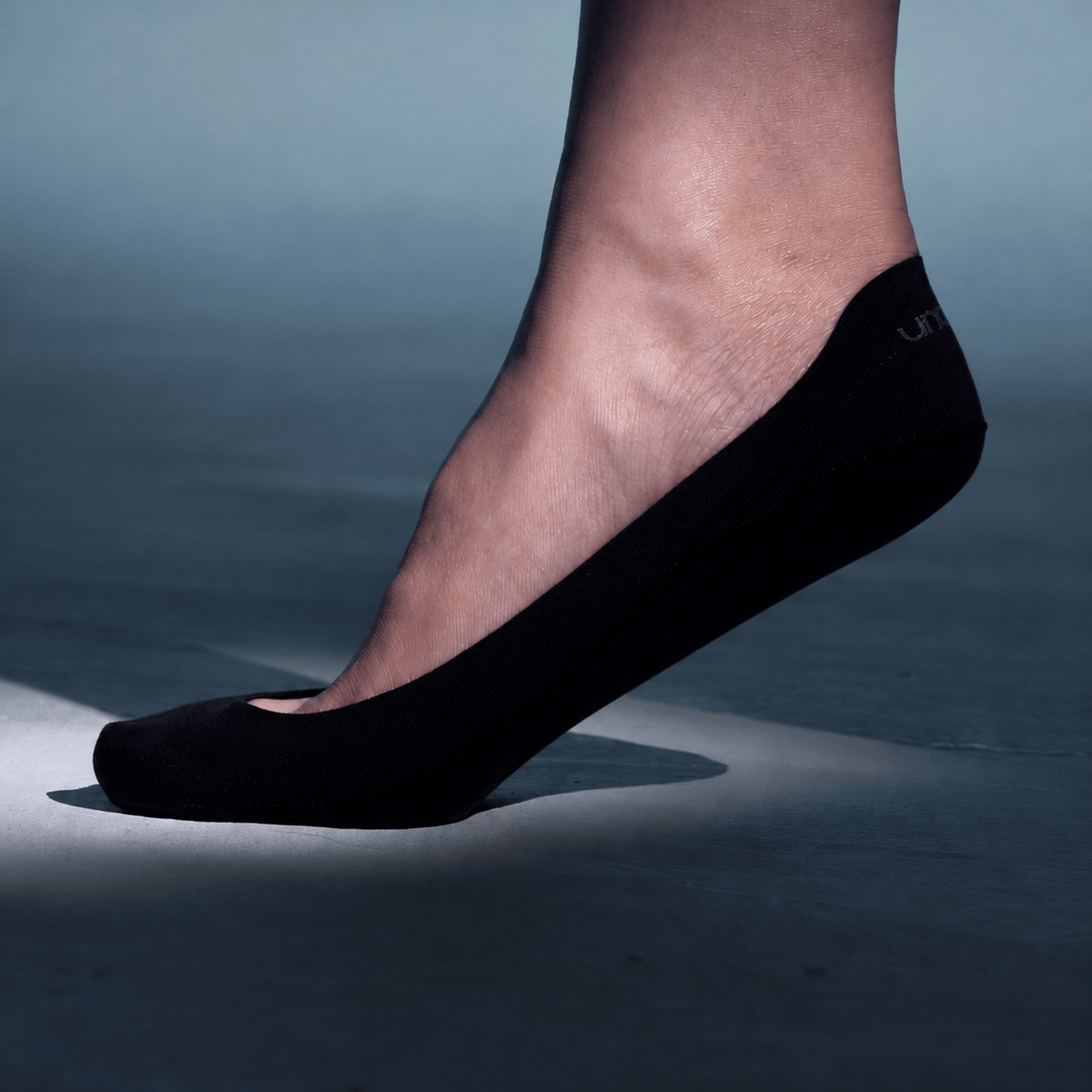 Undercurrent low cut no show sock in black, worn on a foot with the heel lifted