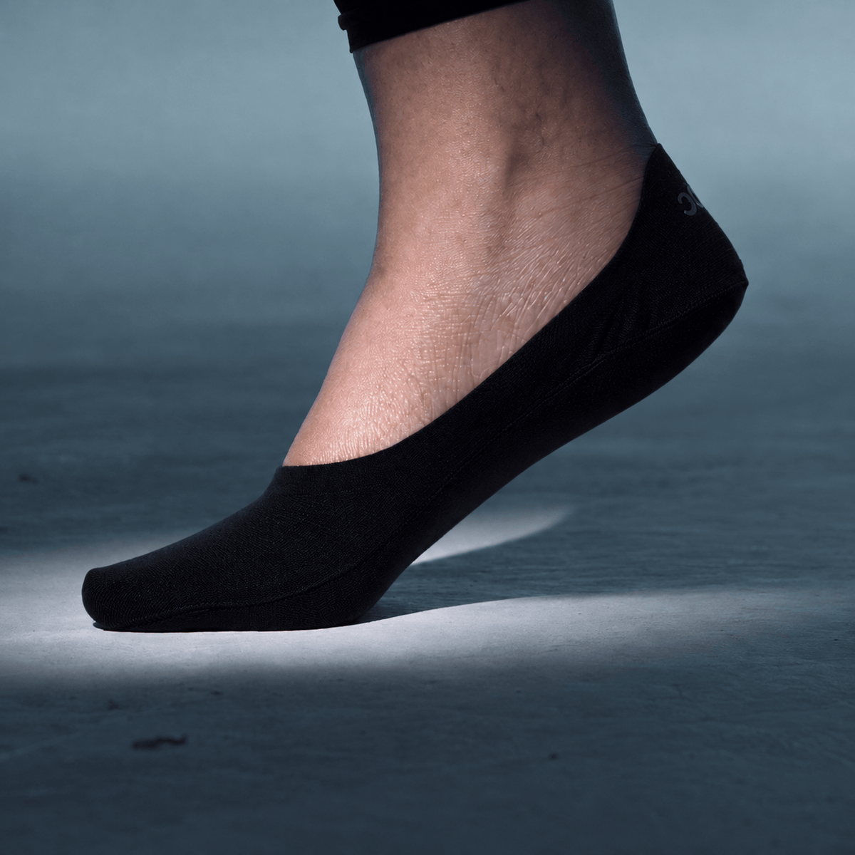 Undercurrent mid cut no show sock in black, worn on a foot with the heel lifted